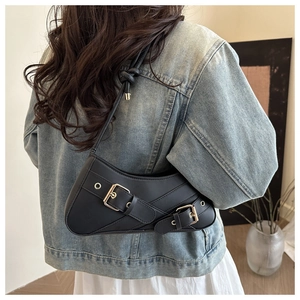 Detail of black matte leather shoulder bag featuring gold buckle and knot strap detail