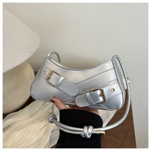 Détail d'un sac hobo argenté avec sangles à boucles et bandoulière à nœuds tressée