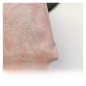 Close-up of pink silk fabric with intricate white floral embroidery on bucket bag