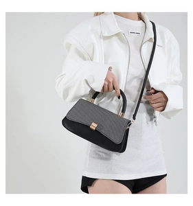 Detail der Handtasche aus grauem Stoff und schwarzem Leder mit Goldverschluss und Griff