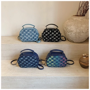 Close-up of patchwork denim shoulder bags in four colors on a stone tiered display