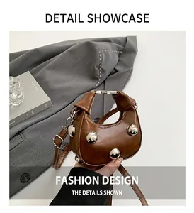 Detailed macro view of brown crescent mini bag with four large silver punk studs