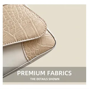 Detailed close-up of beige crocodile pattern leather and smooth ivory stitching on the bag