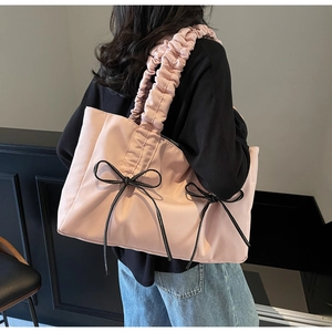 Détail du sac cabas en nylon rose avec anses plissées et petits nœuds noirs