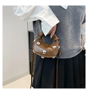 Nahaufnahme braune Halbmond-Handtasche mit Silbernieten und verstellbarem Riemen am Outfit