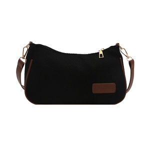 Minimalist black canvas underarm bag with brown leather trim and golden metal hardware
