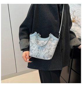 Detail of light blue jacquard bucket bag with floral embroidery and leather trim