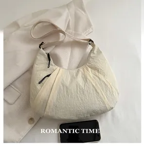 Détail du sac beige plissé avec comparaison de taille à côté d'un smartphone noir