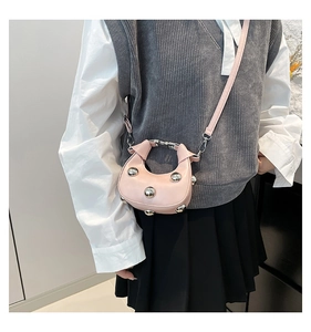 Detail of pink mini dumpling bag with silver metal ball accents worn with casual outfit
