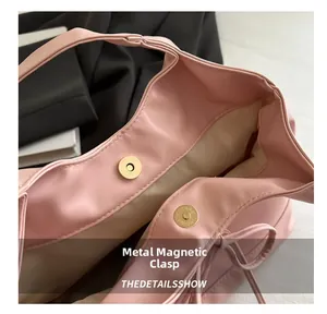 Close-up of pink leather handbag with magnetic snap closure and light gold hardware