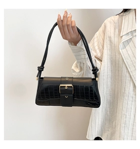 Macro view of black crocodile pattern leather flap with a golden square buckle detail