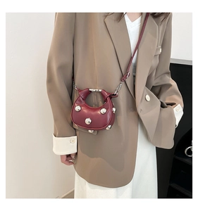 Model wearing a deep burgundy mini crescent handbag with silver stud details and strap
