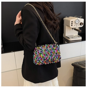 Detailaufnahme einer bunten Pailletten-Kettentasche, getragen zu Blazer und Spitzenkleid
