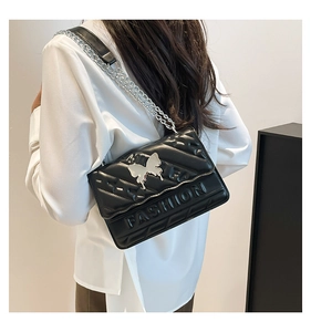Close-up of black quilted leather shoulder bag featuring silver butterfly buckle and chain
