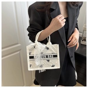 Detailed embroidery of black roses on a white tote bag with elegant lace bow decor