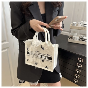Detail of white tote bag with black rose jacquard pattern and lace bow decoration