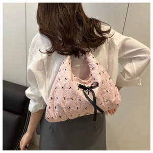 Detail of pink textured hobo bag with black ribbons and silver heart pendant