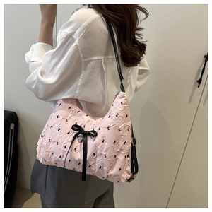 Detail view of pink bubble textured fabric with black bow prints and silver heart charm