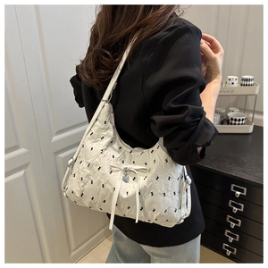 Close-up of beige pleated shoulder bag featuring black rabbit prints and a ribbon bow