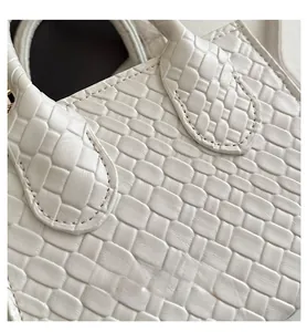 Dettaglio della trama intrecciata e cuciture del manico su borsa bianca in pelle