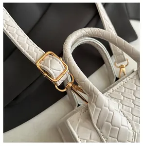 Dettaglio della borsa in pelle intrecciata bianca con fibbia dorata regolabile e marchio