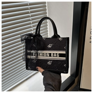 Close-up of black tote bag with rose texture and lace bow detail showing high fashion style