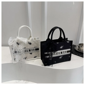 Detailed rose embroidery texture and black-white ribbon on stylish tote bag with lace bow