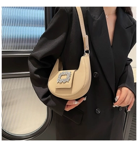 Detail of beige crescent shoulder bag with large silver rhinestone buckle on the flap