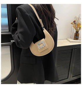 Beige crescent underarm bag with a large rectangular rhinestone buckle shown on model