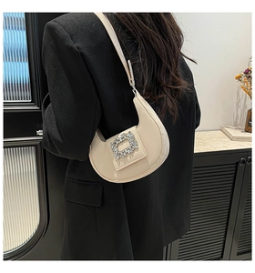 Detail of cream beige crescent underarm bag with sparkling rhinestone square buckle
