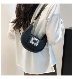 Detail of black crescent shoulder bag with a sparkling rhinestone buckle on a model