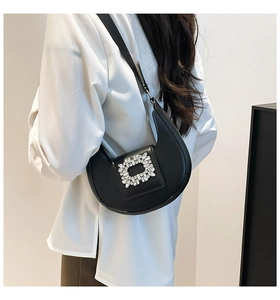 Close-up of a black half-moon shoulder bag featuring a sparkling crystal buckle detail