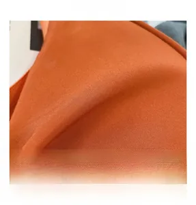 Close-up of bright orange nylon fabric showing fine twill texture and durable material