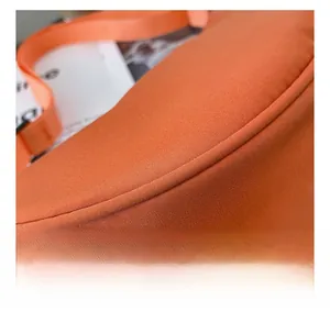Detailed close-up of precise stitching on an orange nylon crossbody crescent bag