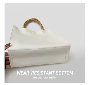 Detail showing the wear-resistant rectangular bottom and stitching of the white leather tote bag