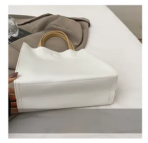 Detail showing the wear-resistant rectangular bottom and stitching of the white leather tote bag