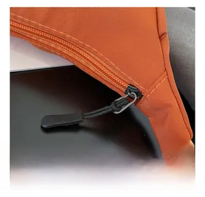 Detail view of smooth black rope zipper pulls on durable orange nylon crossbody bag