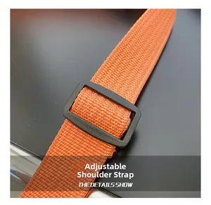 Detail of adjustable orange nylon shoulder strap with black plastic buckle for crossbody bag