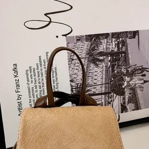 Detail van het bruine lederen handvat op een vintage beige crossbody handtas
