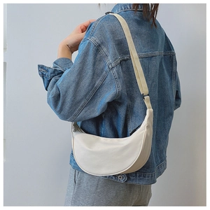 Side view of an off-white crescent nylon hobo bag with adjustable wide strap on model