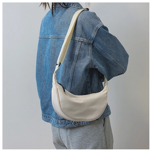 Detailed back view of a cream nylon crescent bag with adjustable strap on a model