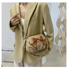 Détail du sac beige avec nœud marron et plis sur un blazer olive pour femme élégante