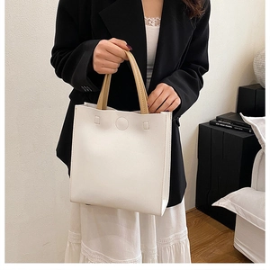Détail d'un sac cabas minimaliste en cuir blanc avec des anses kaki contrastées et fermoir aimanté