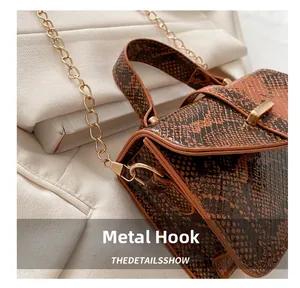 Close-up of golden hardware hook and textured snake skin pattern on the crossbody bag