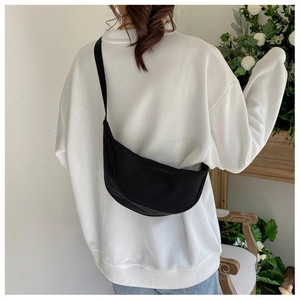 Rear view of model wearing a black crescent nylon crossbody bag with adjustable strap
