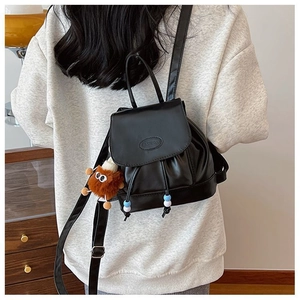 Detail of black PU leather mini backpack with Fashion logo and plush charm accessory