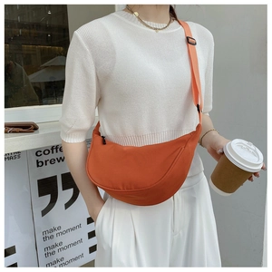 Close-up of bright orange nylon crescent crossbody bag with adjustable wide strap