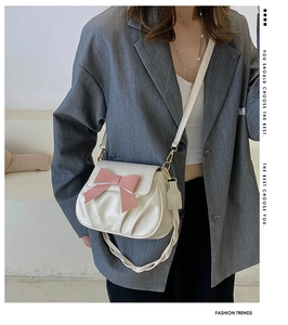 Détail du sac à bandoulière blanc plissé avec un nœud rose et une bandoulière chic