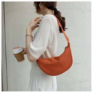 Close-up of orange nylon crescent bag with adjustable strap worn by a model in daily use