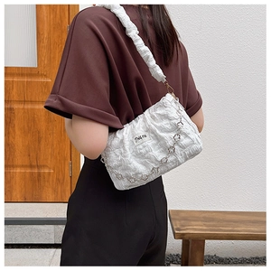 Détail d'un sac à bandoulière blanc plissé avec chaîne florale et sangle en tissu